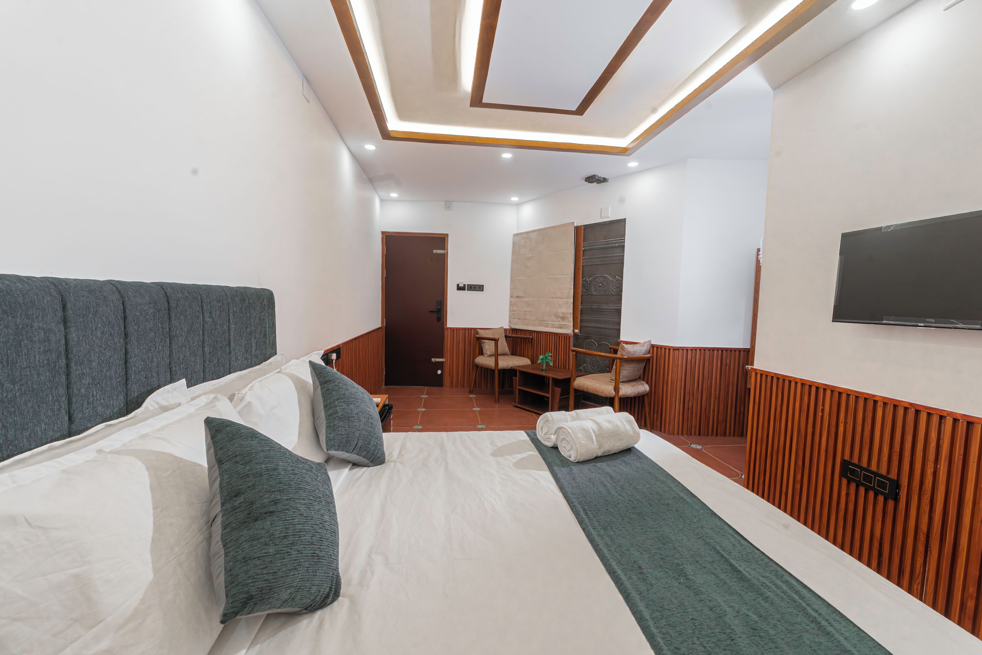 A hotel room with a bed, a desk, a chair, and a television.
