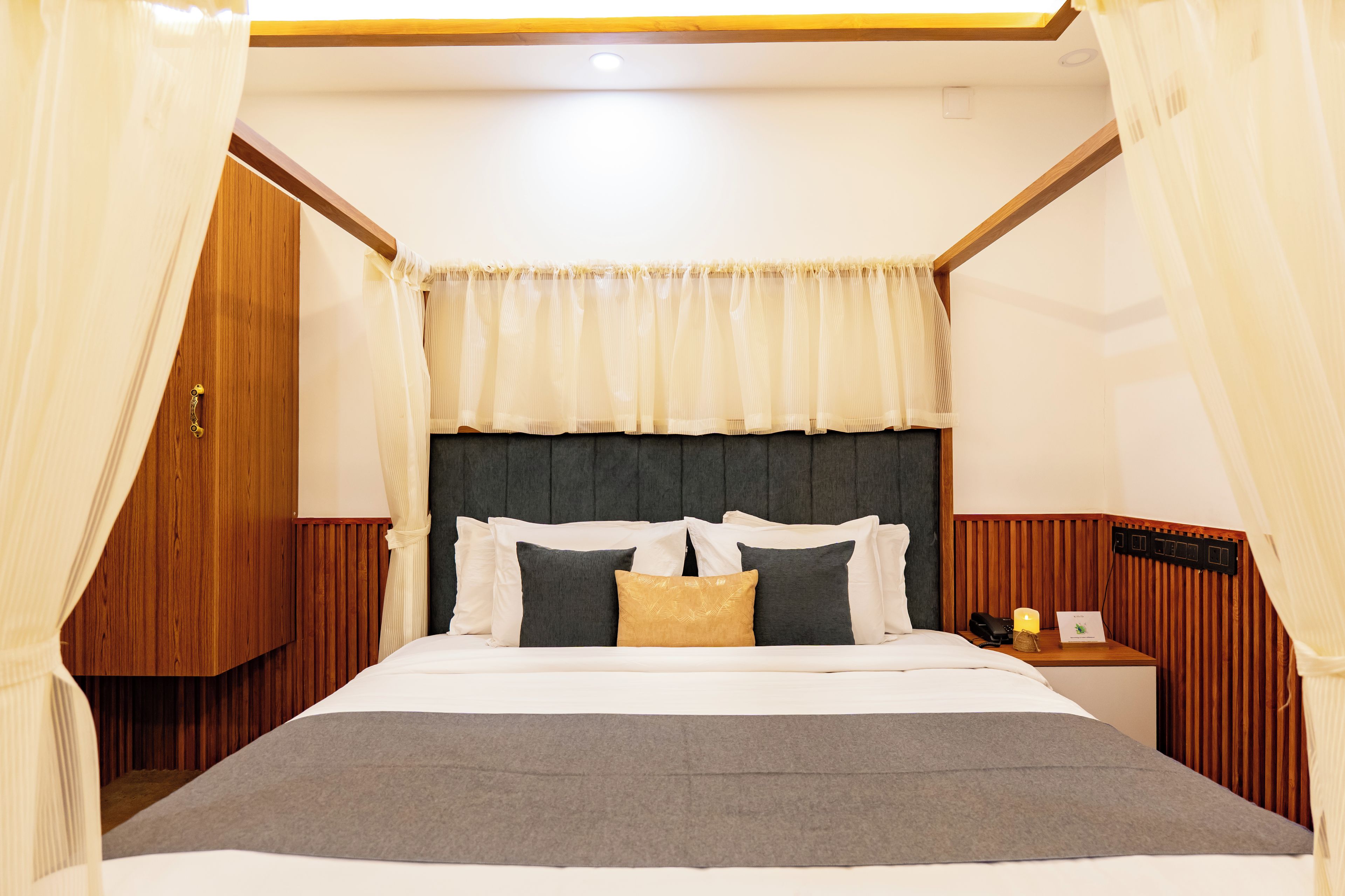 A neatly made bed with a headboard, a bedside table with a lamp, and a curtain.