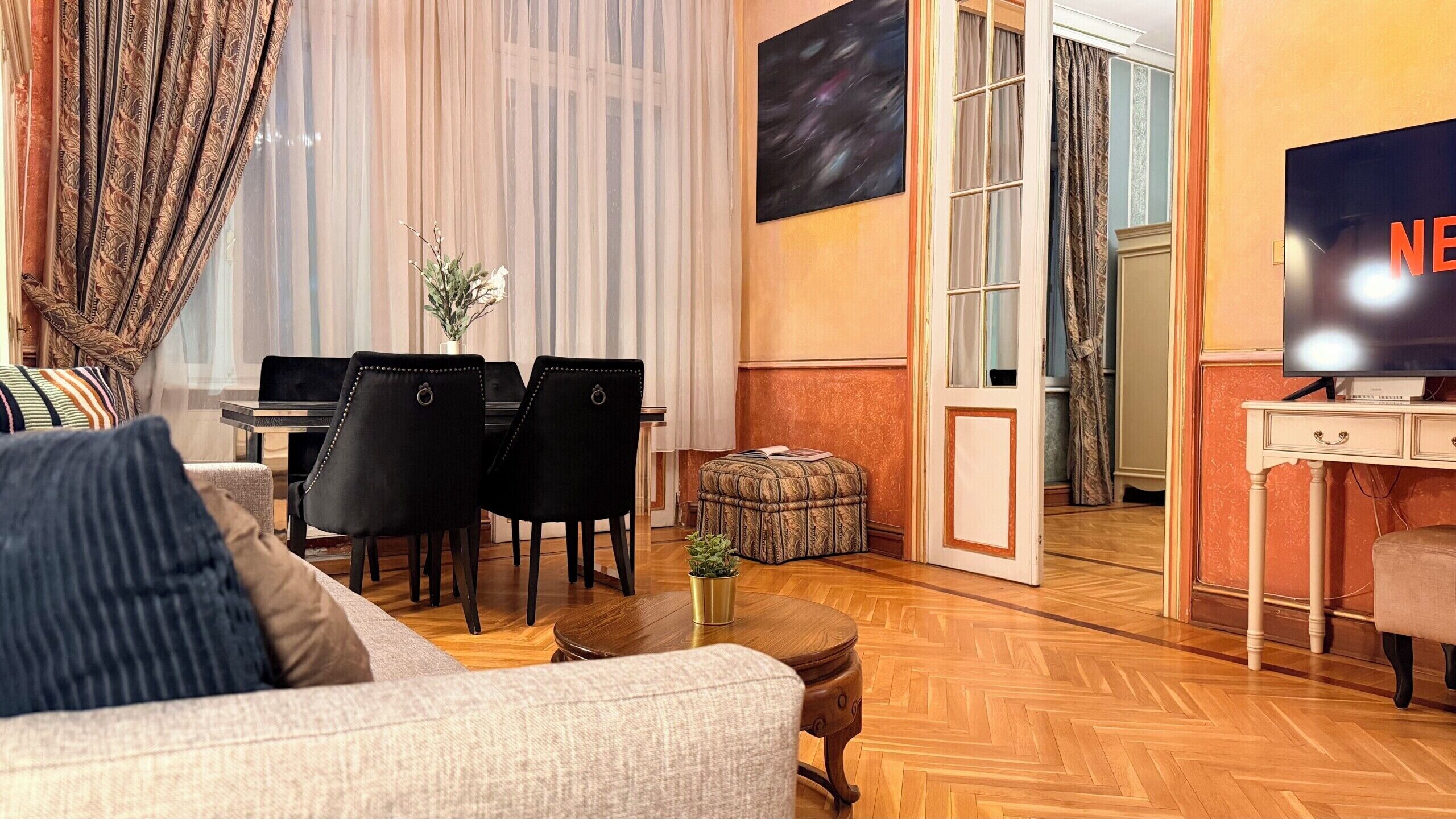 Una sala de estar con sofá, sillas, mesa de centro, televisor y piano.