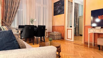 Una sala de estar con sofá, sillas, mesa de centro, televisor y piano.
