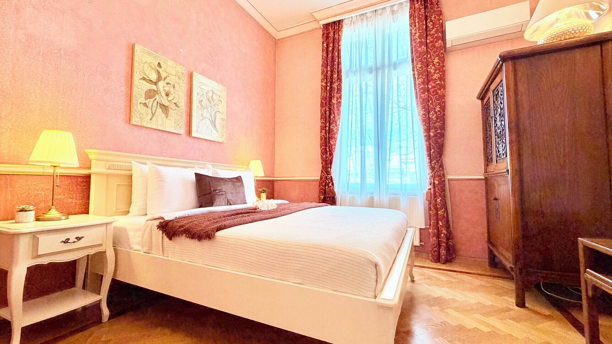 Een slaapkamer met een bed, nachtkastjes, een lamp, een kledingkast en een raam met gordijnen.