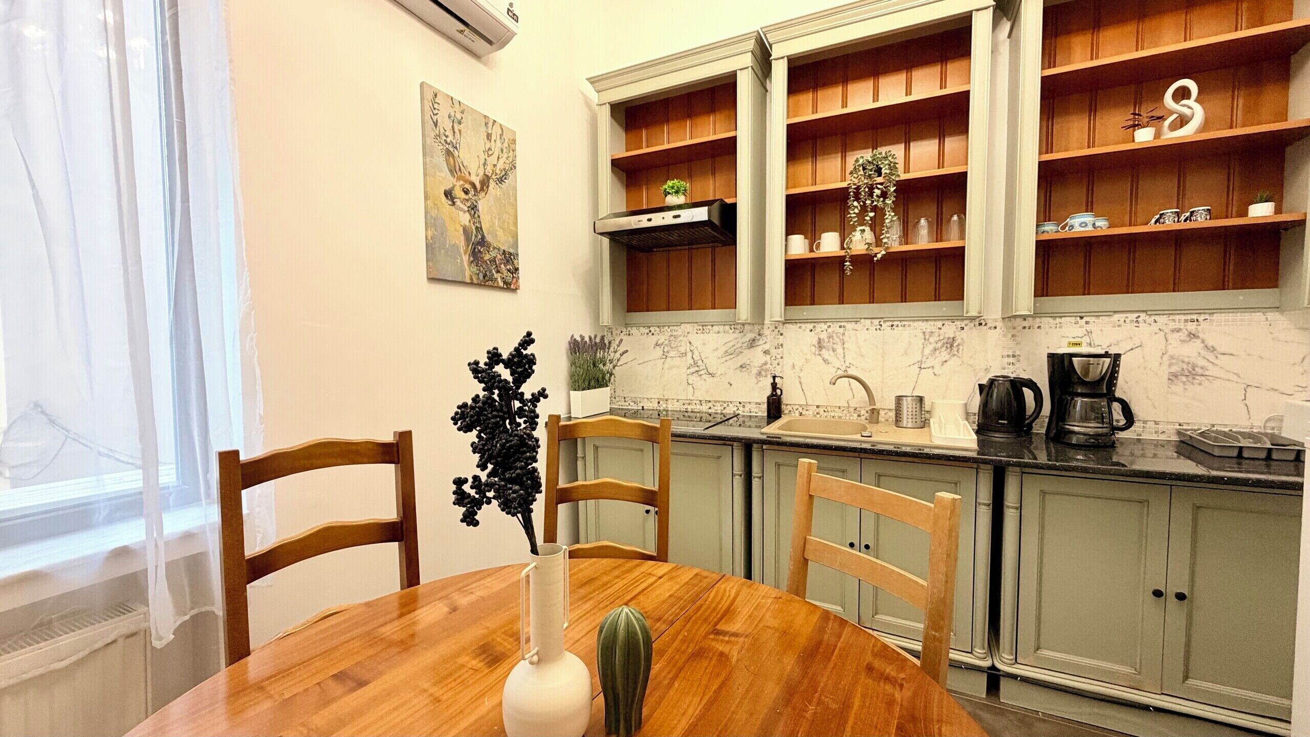 Una cocina con armarios de madera, salpicadero de mármol y una mesa de comedor con sillas.