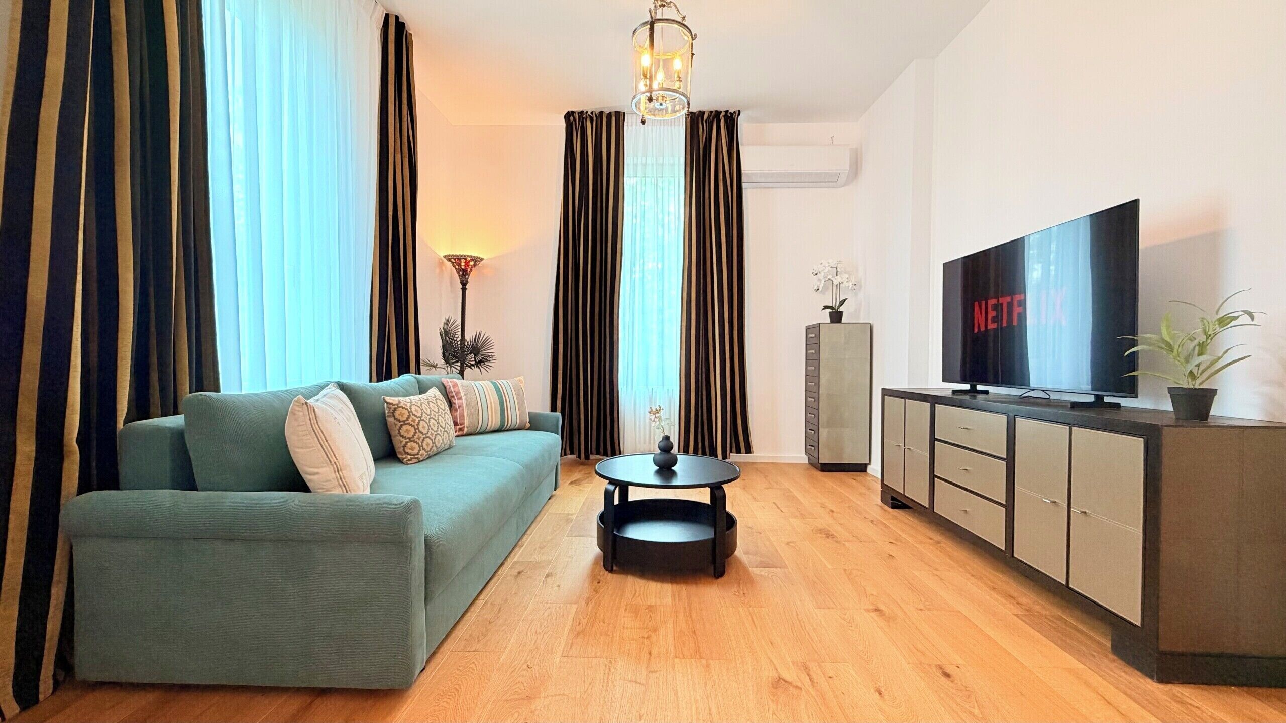 Een moderne woonkamer met een bank, salontafel, televisie en kast.