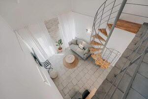 Un espacio moderno para vivir con un sofá, una mesa redonda, una planta en maceta y una escalera de caracol.