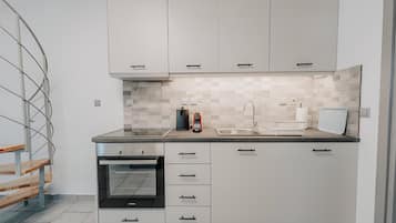 A modern kitchen with white cabinets, a built-in oven, a sink, and a tiled backsplash.