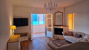 A living room with a chandelier, a sofa, a coffee table, a fireplace, and a television. - Fully renovated apartment in the heart of Propriano (Propriano)
