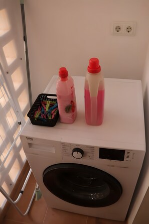 A front-loading washing machine with a control panel and two bottles of detergent on top. - Apartment 'Casa Maje' with Shared Terrace and Wi-Fi (Fuente Álamo de Murcia)