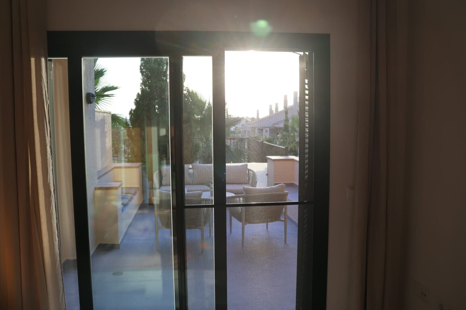 A sliding glass door leading to a balcony with outdoor furniture and a view of a residential area.