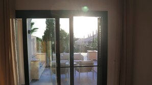A sliding glass door leading to a balcony with outdoor furniture and a view of a residential area.