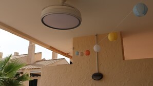 A ceiling fan, a wall-mounted light fixture, and a string of paper lanterns.