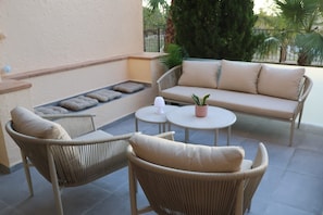 Ein Patio mit Korbmöbeln, einer Couch und einem kleinen Tisch mit einer Pflanze.