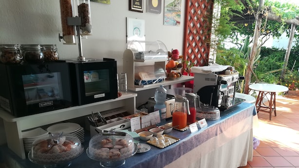 A breakfast buffet with a coffee machine, a water dispenser, and a variety of food items.