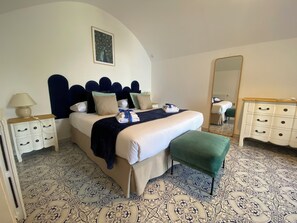 Una habitación de hotel con una cama, una mesita de noche, un aparador, un espejo y un suelo estampado.
