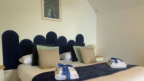 A neatly made bed with a dark headboard, multiple pillows, and folded towels on the side.
