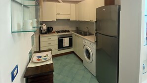 A compact kitchen with a washing machine, a refrigerator, and a stove.
