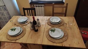 Ein Holztisch gedeckt mit vier Tellern, einer Weinflasche und Gläsern.