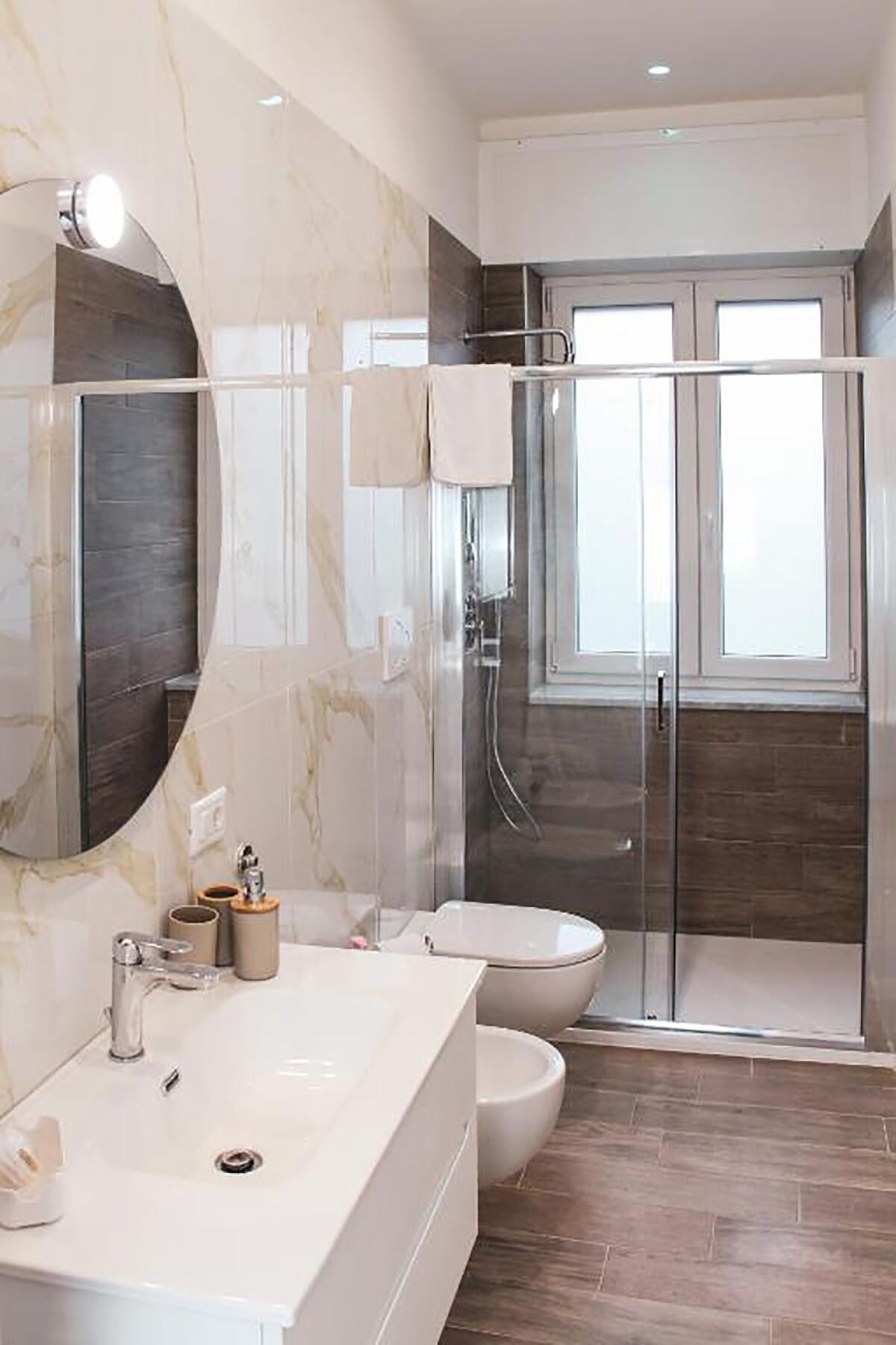 A modern bathroom with a large mirror, a glass shower enclosure, and a white sink.