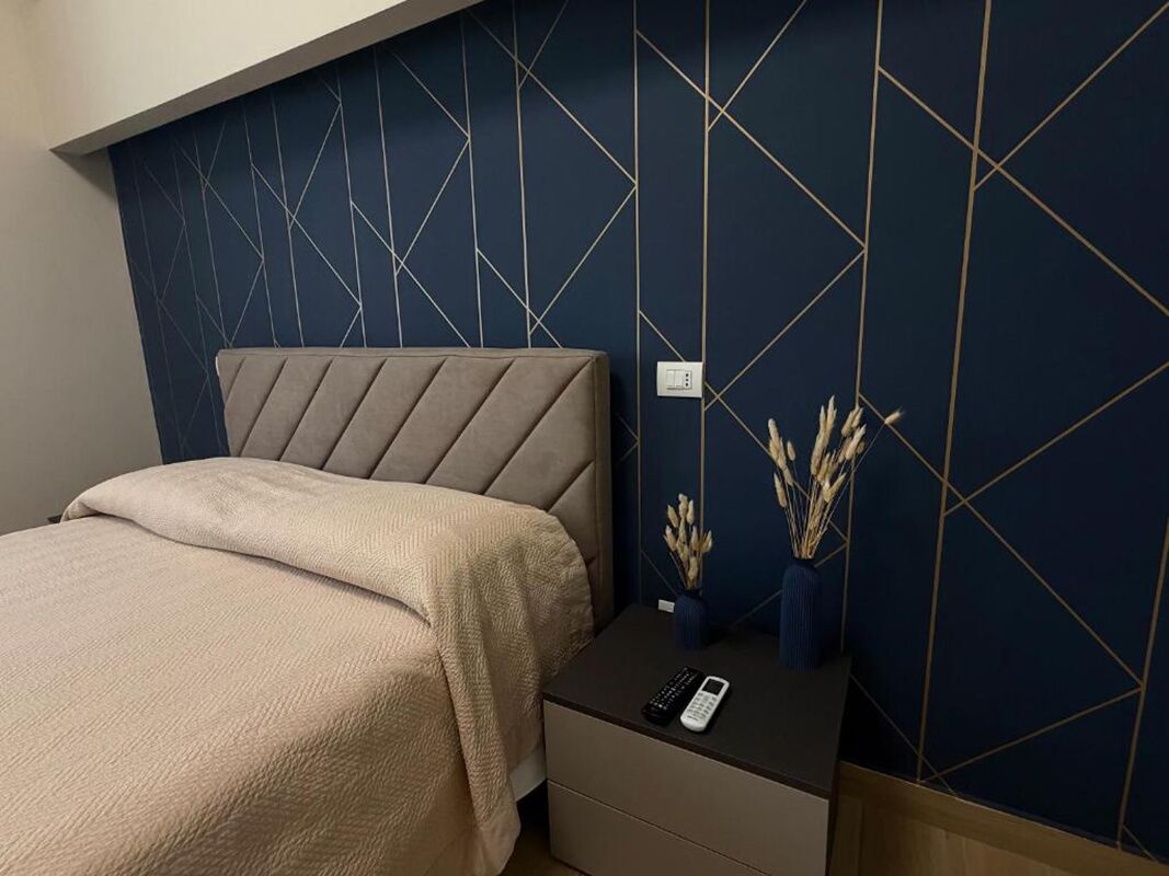Une chambre à coucher avec un lit, une table de chevet et un mur orné de motifs géométriques.