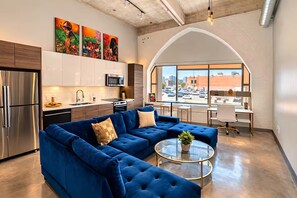 Uma sala de estar moderna com um sofá seccional, uma mesa de centro de vidro e vista da cidade por grandes janelas.