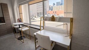 Ein moderner Arbeitsbereich mit weißen Schreibtischen, Stühlen und einem großen Fenster mit Blick auf eine Skyline.
