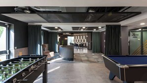 A modern indoor recreational area with foosball tables, a pool table, and a bar area. - Student Only New Park - Edinburgh (Edinburgh)