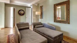 Ein Wohnzimmer mit zwei Sofas, einem gemusterten Teppich, einem Gemälde, einer Lampe und einem Spiegel an der Wand.