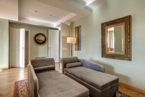 A living room with two sofas, a patterned rug, a painting, a lamp, and a mirror on the wall. - Luxury Riverside Apartment with Arno Views, Balconies & Private Garage (Firenze)