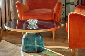A round glass table with a metal base, a red velvet armchair, and a wooden floor. - Luxury Riverside Apartment with Arno Views, Balconies & Private Garage (Firenze)