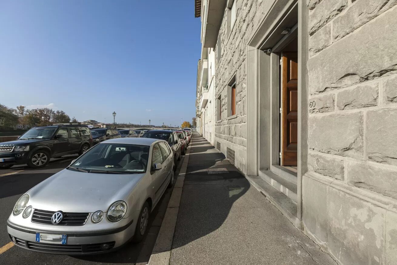Una fila de autos estacionados junto a un edificio de piedra bajo un cielo despejado.