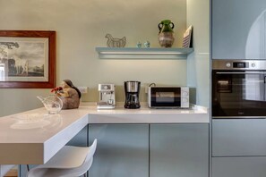 A modern kitchen with a white countertop, a coffee maker, a microwave, and an oven. - Luxury Riverside Apartment with Arno Views, Balconies & Private Garage (Firenze)