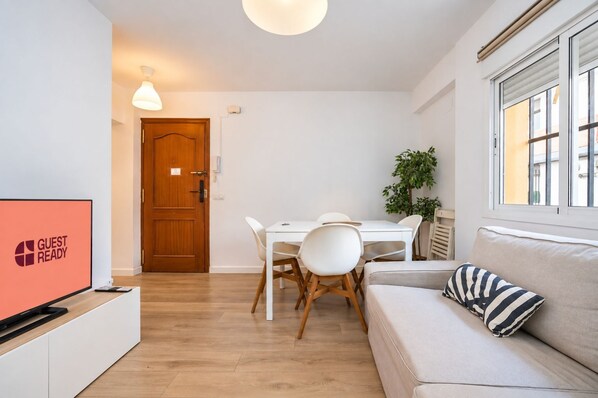 Un salon moderne avec un canapé, une table à manger et des chaises, un téléviseur et une porte en bois.