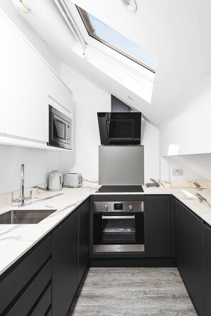 A modern kitchen with a skylight, a microwave, a stove, and a built-in oven. - Panoramic View by MyCityHaven (Redland)