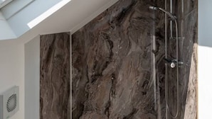 Ein Oberlicht über einer Dusche mit Marmorwänden.
