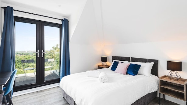 Ein modernes Hotelzimmer mit einem großen Bett, einem Schreibtisch und Blick durch eine Schiebetür.