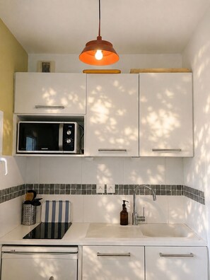 A modern kitchen with a microwave, a sink, and a hanging light fixture. - Cozy loft in Anglet - Quiet balcony - Private parking (Anglet)