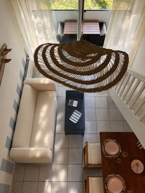 A room with a sofa, a dining table set for two, and a hanging woven light fixture. - Cozy loft in Anglet - Quiet balcony - Private parking (Anglet)