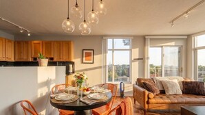 Une cuisine moderne avec des meubles en bois, une table à manger avec des chaises orange et un canapé en cuir.