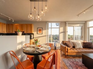 Eine moderne Küche mit Holzschränken, einem Esstisch mit orangefarbenen Stühlen und einem Ledersofa.