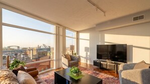 Un salon moderne doté d’une grande fenêtre, d’un téléviseur à écran plat et d’un canapé.