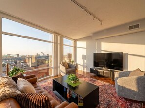 Ein modernes Wohnzimmer mit großem Fenster, Flachbildfernseher und einer Couch.