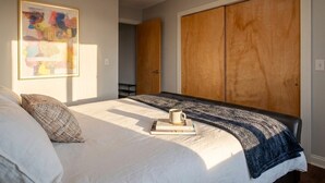Une chambre à coucher avec un lit, une grande armoire et un tableau abstrait encadré accroché au mur.