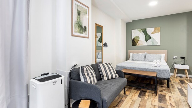 A modern bedroom with a bed, a sofa, a mirror, and a heater.