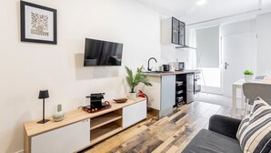 A modern kitchen with a flat-screen TV, a coffee machine, and a sink.
