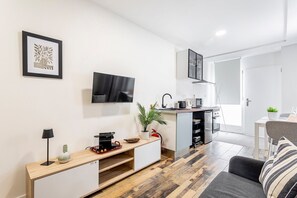 A modern kitchen with a flat-screen TV, a coffee machine, and a sink.