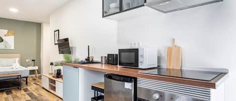 Una cocina moderna con horno empotrado, microondas y campana extractora de acero inoxidable.
