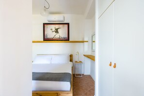 A bedroom with a bed, a bedside table, a framed artwork, a wardrobe, and a bathroom with a mirror and towel rack. - Pazzariello Roof by NapoliApartments (Naples)