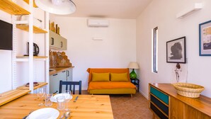 Ett kompakt bostadsutrymme med ett matbord, en soffa, en TV och ett litet kök.