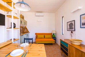 A compact living space with a dining table, a sofa, a TV, and a kitchenette. - Pazzariello Roof by NapoliApartments (Naples)
