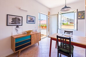 A dining area with a wooden table, chairs, and a view through an open door to the outside. - Pazzariello Roof by NapoliApartments (Naples)