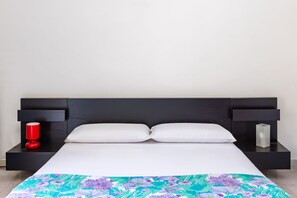 A bed with a white mattress and two pillows, flanked by black nightstands with a red and a white object on each. - PizzArcHouse - One Bedroom Apartment, Sleeps 4 (Naples)